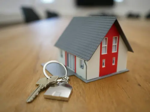 Llavero con una casa en miniatura sobre una mesa de madera